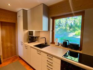 a kitchen with a sink and a large window at Ferienhaus Eichenseer Gallzein - Alleinlage mit Garten, Wald & Bergblick in Gallzein