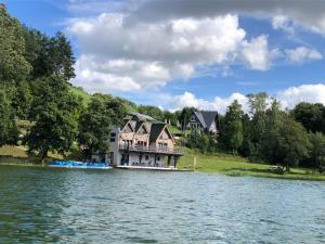 a large house sitting on the side of a lake at MODRA SOBÓTKA - Perła KASZUB in Ręboszewo