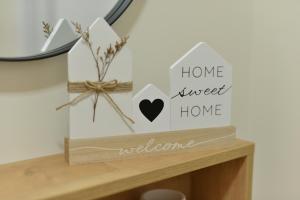 a shelf with a sign that reads home sweet home welcome at Ivy apartman Vršac in Vršac