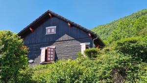 a black house with a red window and trees at Les Fougères in Sévrier