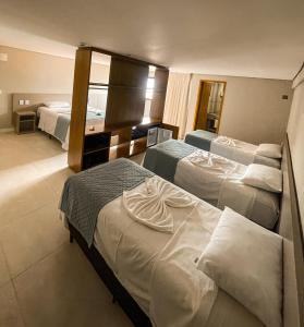 una camera d'albergo con tre letti e un bagno di HIMMA Hotel a Aparecida