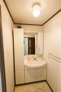 泉佐野市にあるゲストハウス 泉のバスルーム(白い洗面台、鏡付)