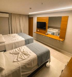 una camera d'albergo con due letti e uno specchio di HIMMA Hotel a Aparecida