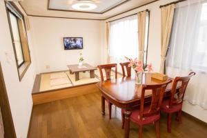 a dining room with a wooden table and chairs at Guest House Izumi in Izumi-Sano