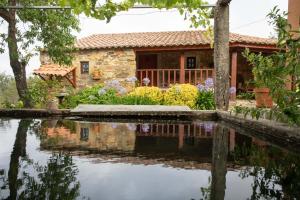 a stone house with a pond in front of it at Casa do Dão in Oleiros