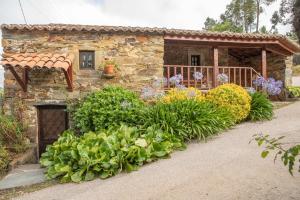 a stone house with flowers in front of it at Casa do Dão in Oleiros