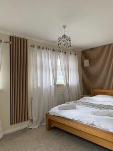 a bedroom with a bed with white curtains and a chandelier at Mountain View in Merthyr Vale +13 photos