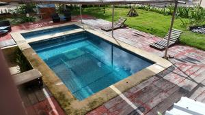 a swimming pool with two chairs and an umbrella at Eco Cabañas Bluekay in Mahahual