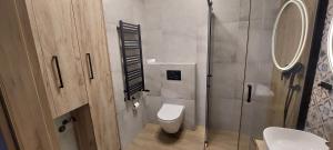 a bathroom with a toilet and a glass shower at Apartament Podjasnogórski Loretańska in Częstochowa +6 photos