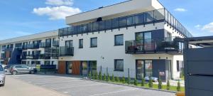 a white building with a balcony and a parking lot at Apartament Podjasnogórski Loretańska in Częstochowa