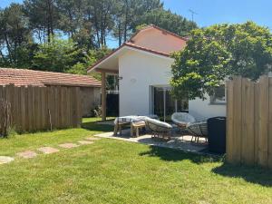 a backyard with a table and chairs and a fence at Maison de vacances Helios in Seignosse