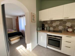 a kitchen with white cabinets and a room with a bed at Appartement avec espace jacuzzi et terrasse in Rians