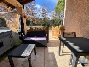 a patio with two chairs and a table and a bench at Appartement avec espace jacuzzi et terrasse in Rians