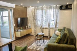a living room with a couch and a tv at Apartman KATY - self check-in, besplatan parking, blizu centra in Vukovar