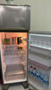 a refrigerator with its door open with drinks and water bottles at Mini apê de luxo montese in Fortaleza