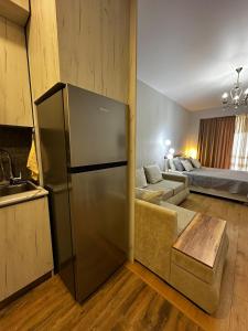 a kitchen with a refrigerator and a living room with a couch at Luxury Residence Likani in Borjomi