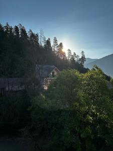 a house in the middle of trees with the sun setting at Luxury Residence Likani in Borjomi