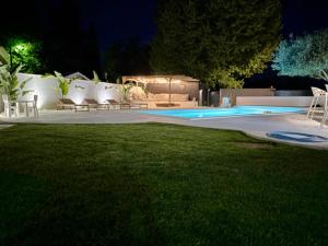 a swimming pool at night with chairs and a lawn at studio indépendant dans une villa in Aimargues