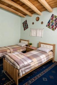 two beds in a room with wooden ceilings at Asraf village guesthouse in Aydar Kul’
