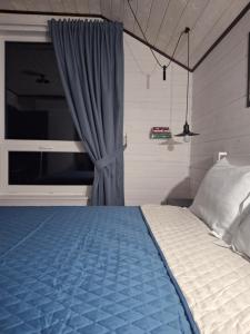 a bedroom with a bed with a blue blanket and a window at Bukhouse Carpathians in Krivorovnya