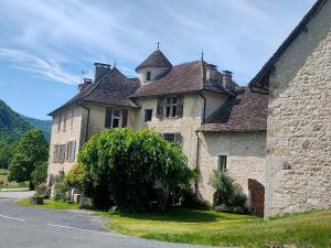 an old stone building with a tree in front of it at La Maison bleue in Rossillon