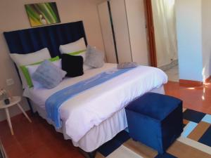 a blue and white bed with pillows and a blue stool at Ecogreen on End in Northam