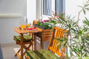 a table with two glasses of orange juice and some plants at Villa ELENA Room Old Town in Rogoznica