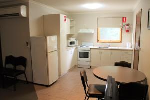 a small kitchen with a table and a white refrigerator at Ballarat Eureka Lodge Motel in Ballarat