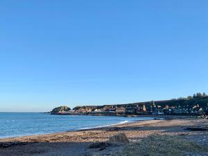 a beach with the ocean and buildings in the background at The Auld Bakehouse in Stonehaven +8 photos