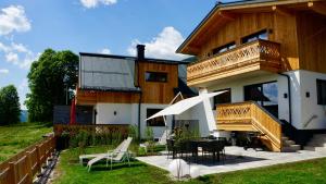 a house with a balcony and a table and chairs at das korda - Ferienhaus & Sommercard in Ramsau am Dachstein