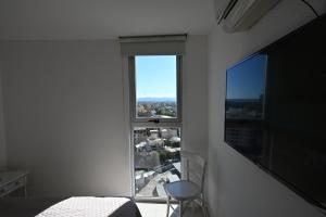 a bedroom with a view of a city from a window at ALOHA Güemes Premium, 2 dorm con Vista a las Sierras in Córdoba +28 photos