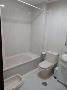 a white bathroom with a toilet and a bath tub at ZiRALLA in Allariz