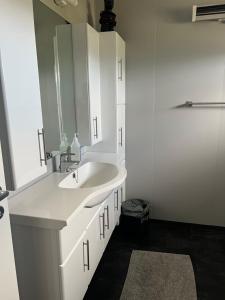 a white bathroom with a sink and a mirror at Huset Heimstad i Herfjord in Skippervik