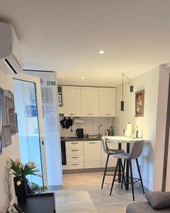 a kitchen with white cabinets and a table and chairs at Apartman NONO in Splitska