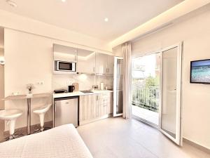 a kitchen with white cabinets and a large window at The Corfu Urban Stays in Ágios Rókkos