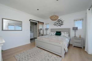 a white bedroom with a bed and a mirror at Cassa Dunnage At Pezula in Knysna