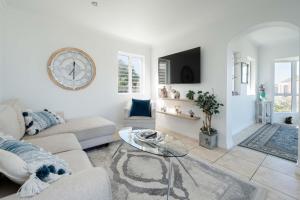 a living room with a couch and a clock on the wall at Cassa Dunnage At Pezula in Knysna