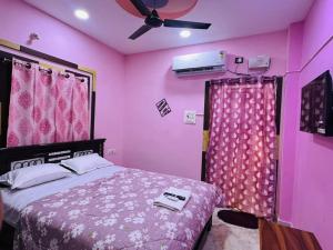 a pink bedroom with a bed and a ceiling fan at ss luxe inn in Guntūr