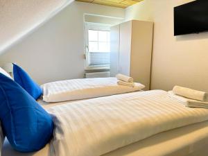 two beds with blue pillows in a room at ANKERHUUS Norddeich in Norddeich