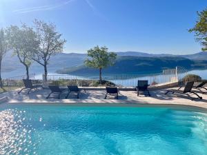 a swimming pool with chairs and a view of the water at Domaine de la Ferme Para Lou in Sainte-Croix-de-Verdon