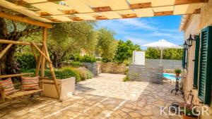 a patio with a wooden pergola and a table and an umbrella at Private Villa Demetra 1768 with pool - close to Fiskardo in Fiskardo
