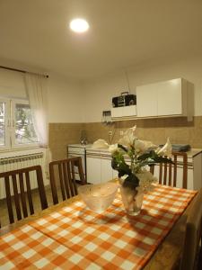 a kitchen with a table with a vase of flowers on it at Vikendica Tobi in Čapljina +4 photos