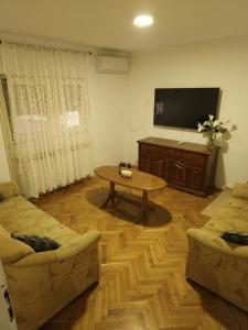 a living room with a table and a flat screen tv at Vikendica Tobi in Čapljina