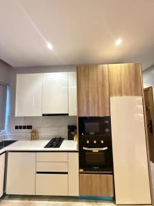 a kitchen with white cabinets and a black appliance at Starella Apartments in Lekki +2 photos