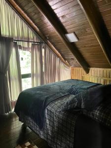a bedroom with a bed in a wooden ceiling at Chalé Manacá da Serra in São Bento do Sul