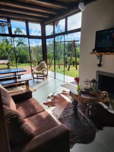 a living room with a couch and a tv at Chalé Manacá da Serra in São Bento do Sul