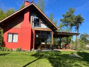 a red house with a dog laying in front of it at Chalé Manacá da Serra in São Bento do Sul