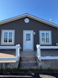 a black house with a white door and two windows at Brooks Place in Deer Lake
