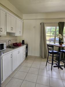 a kitchen with white cabinets and a table and a window at Riseland Breeze Collection in Carnbee Village