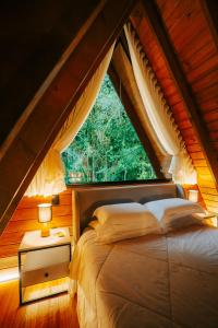 a bed in a room with a large window at Lumine Cabanas- Chalé na Serra Gaúcha in Farroupilha